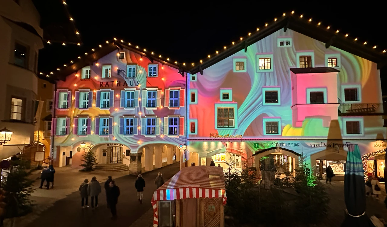 Bunte Fassadenprojektionen über einer Passage im nächtlichen Kitzbühel
