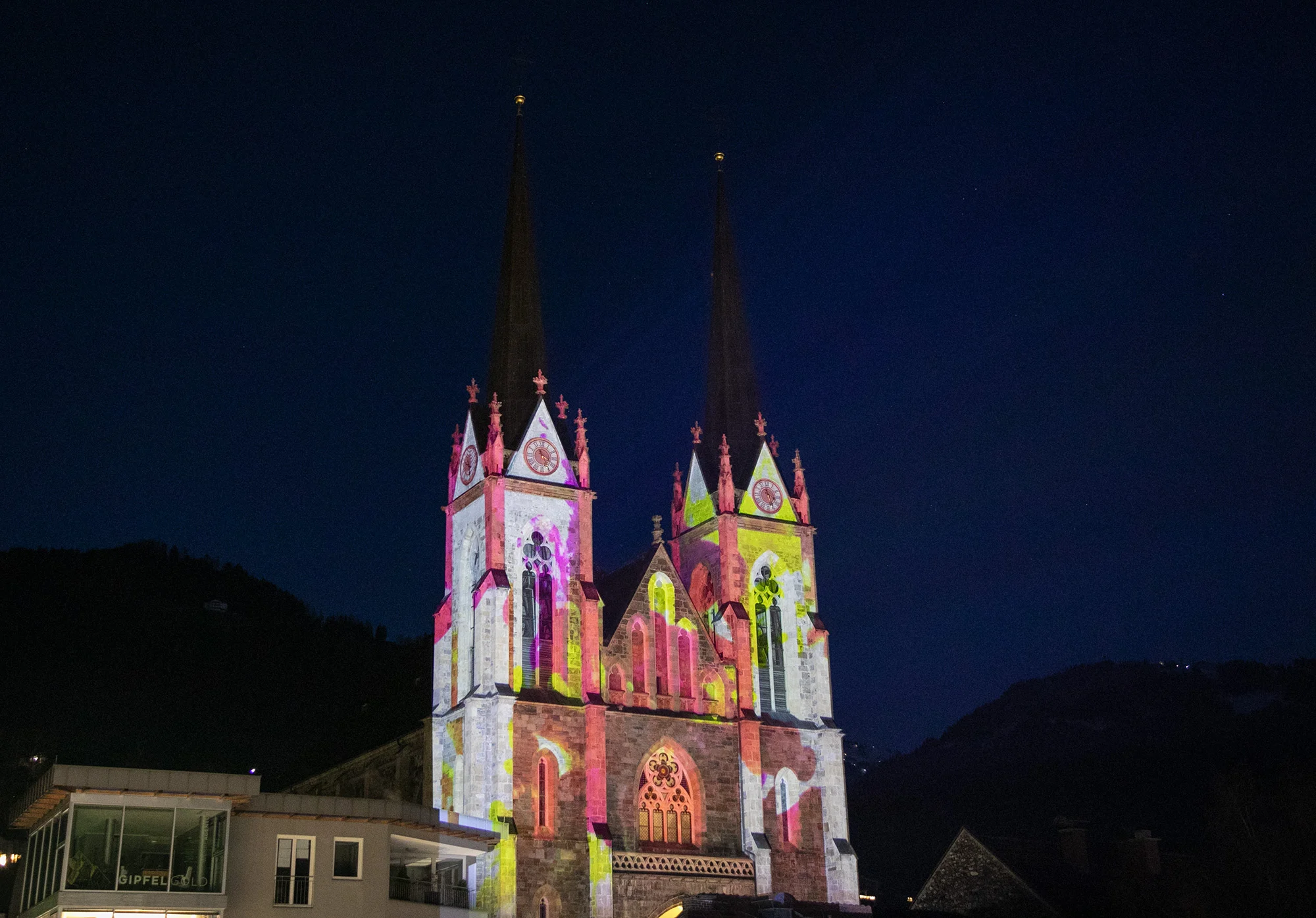 Weite Abendansicht des Pongauer Doms mit bunten Fassadenprojektionen