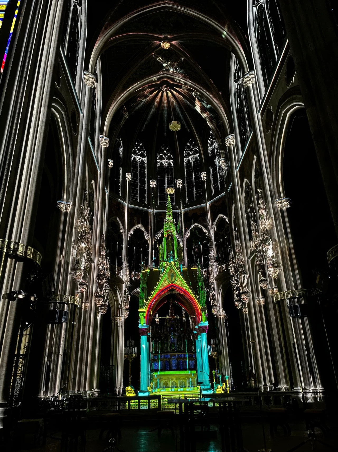 Colourfully projected church arch in dark surroundings – LIGHT OF CREATION, Votivkirche, Vienna, Austria
