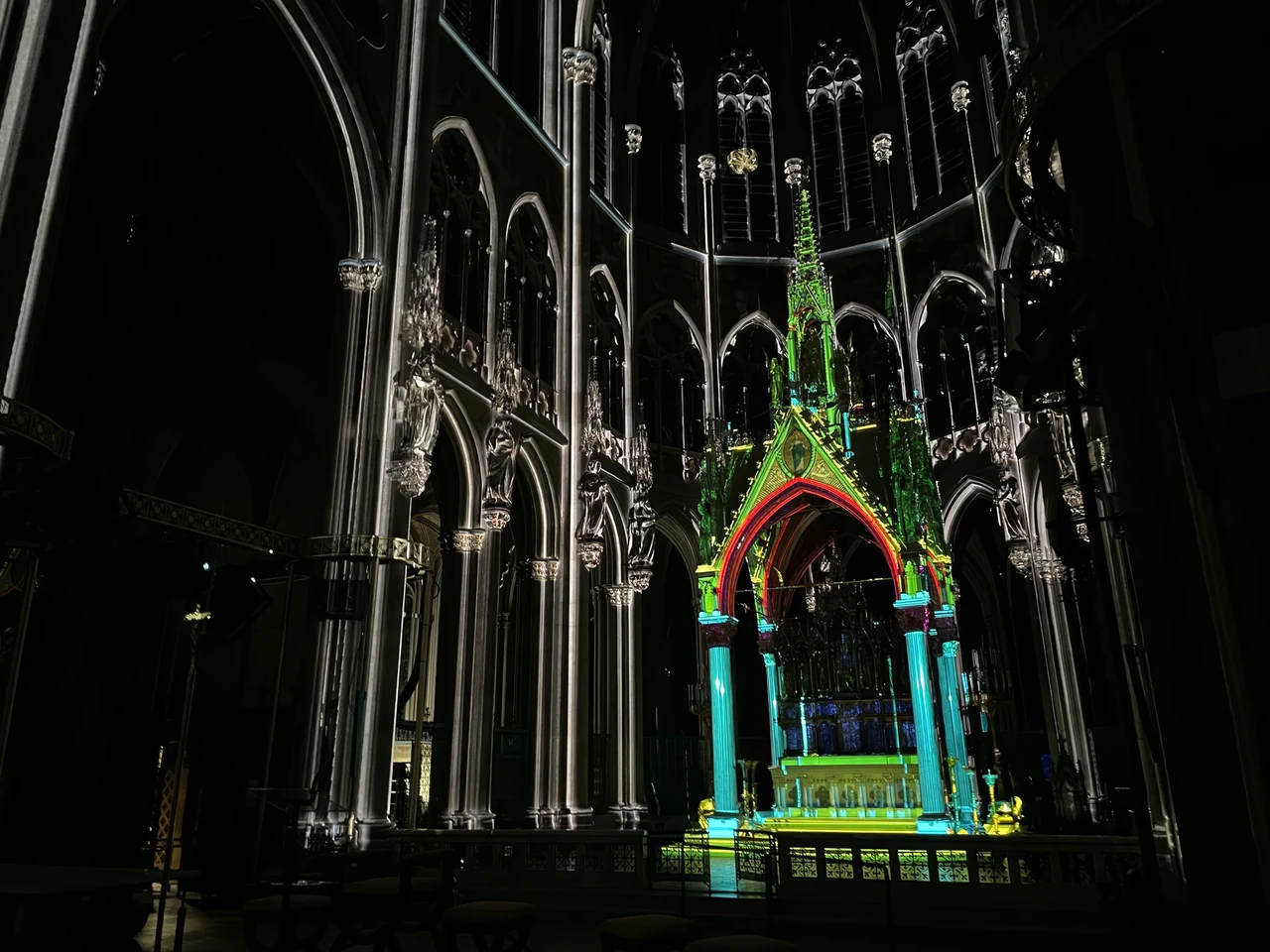 Colourfully projected church arch in dark surroundings – LIGHT OF CREATION, Votivkirche, Vienna, Austria
