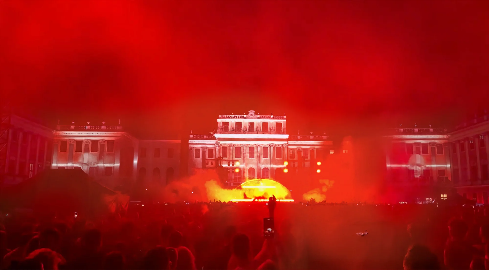 Rotes Bühnenlicht und Publikum vor der beleuchteten Schlossfassade