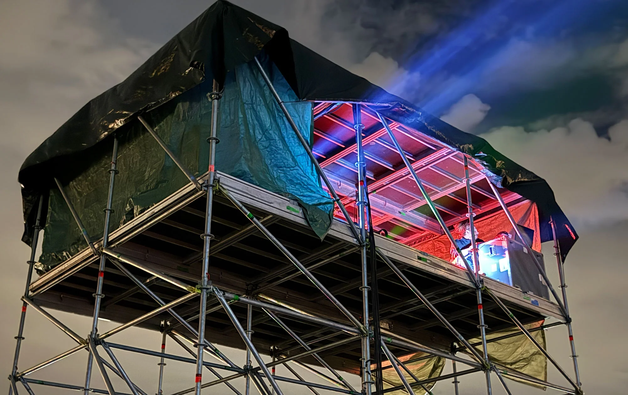 Projektionsaufbau auf einer Gerüstplattform mit Lichtstrahl zum Himmel