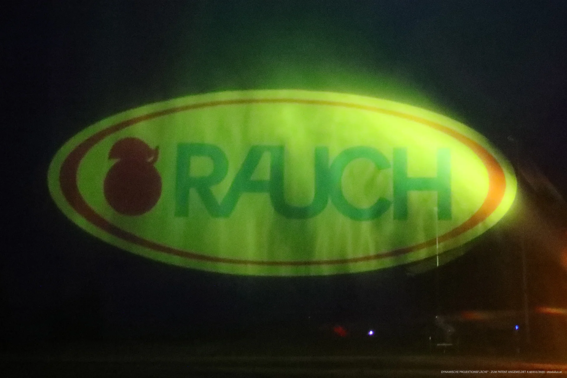 Gelb-grünes RAUCH-Logo auf einer Projektionsfläche aus Wasserpartikeln