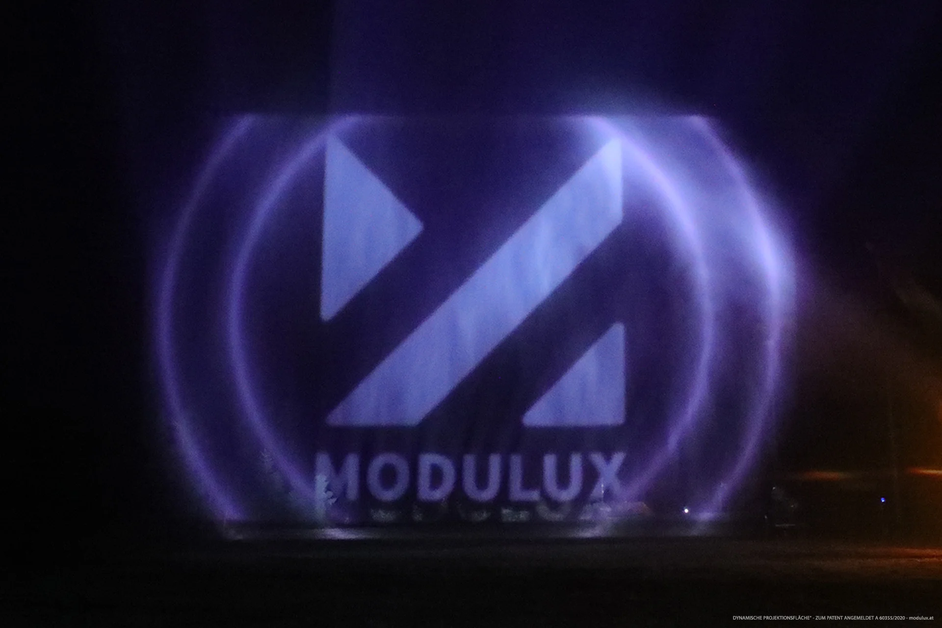 MODULUX-Schriftzug und geometrisches Logo auf violett beleuchteten Wasserpartikeln