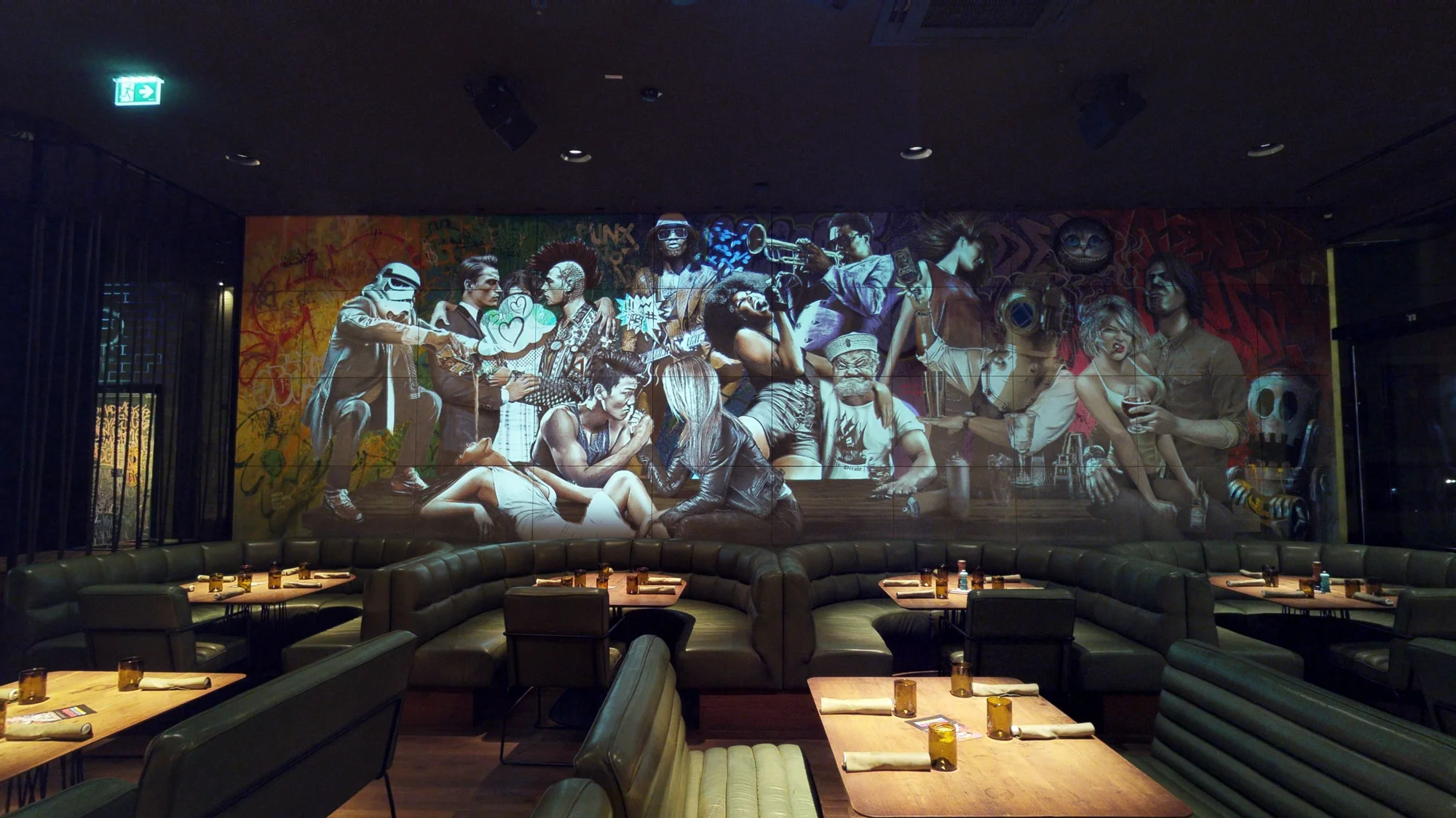 Projektion auf das Figuren-Mural hinter den Sitzgruppen der Spelunke Wien