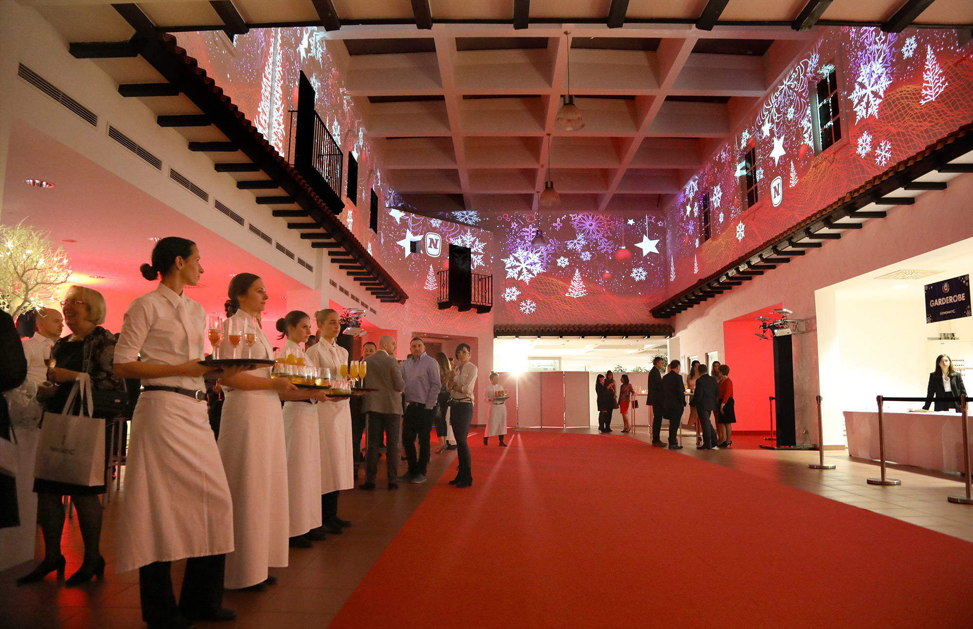 Schneeflocken- und Markenprojektionen im rot beleuchteten Foyer – Novomatic, Pyramide, Vösendorf, Österreich