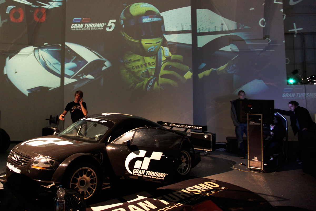 Ausgestelltes Gran-Turismo-Auto vor projizierten Spielmotiven – Sony PlayStation, Ovalhalle, MuseumsQuartier, Wien, Österreich