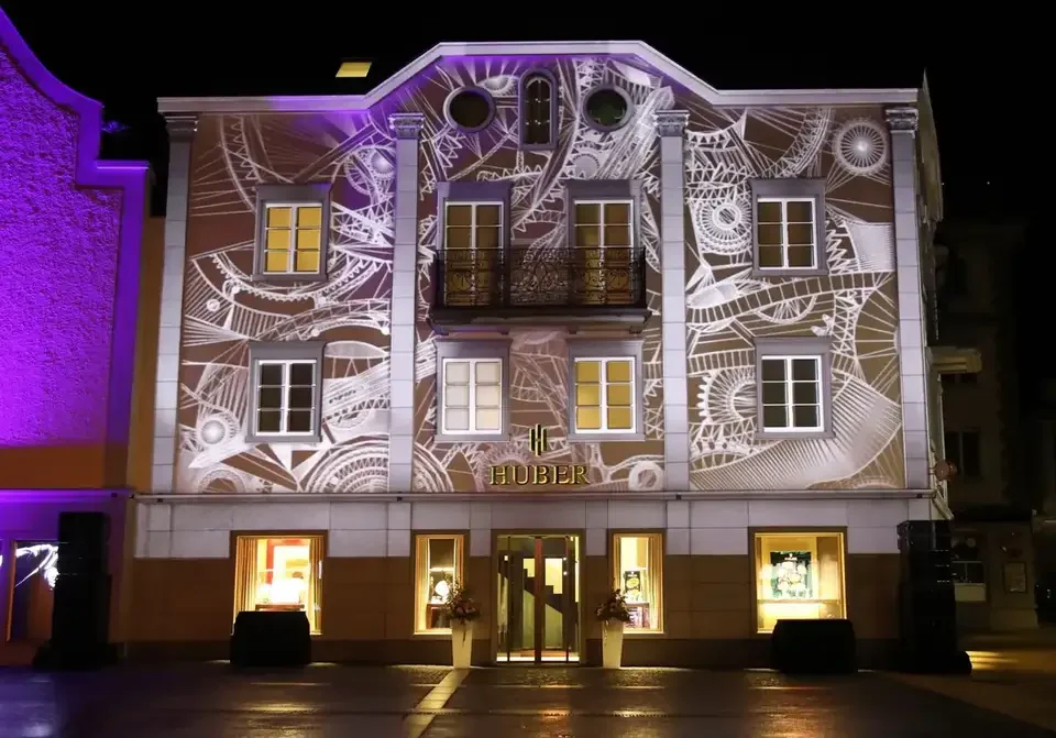 Uhrwerk und Zahnräder als Projektion auf die Fassade – HUBER OPENING, Huber Fine Watches & Jewellery, Bregenz, Österreich