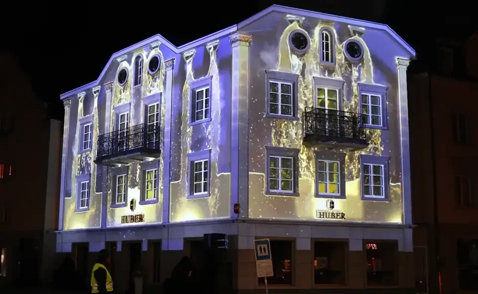 Uhrwerk und Zahnräder als Projektion auf die Fassade – HUBER OPENING, Huber Fine Watches & Jewellery, Bregenz, Österreich