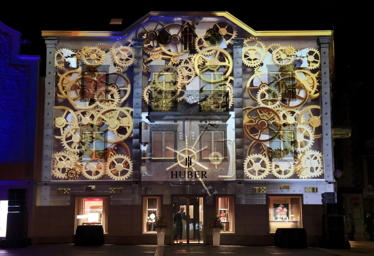 Uhrwerk und Zahnräder als Projektion auf die Fassade – HUBER OPENING, Huber Fine Watches & Jewellery, Bregenz, Österreich