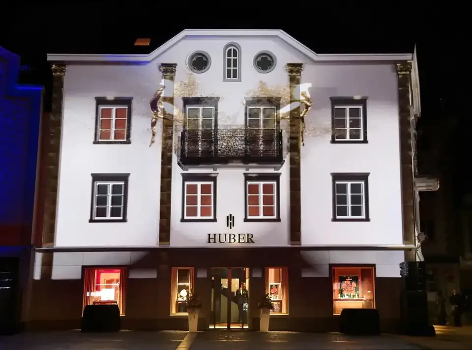 Weiße Fassadenprojektion mit architektonischen Konturen – HUBER OPENING, Huber Fine Watches & Jewellery, Bregenz, Österreich
