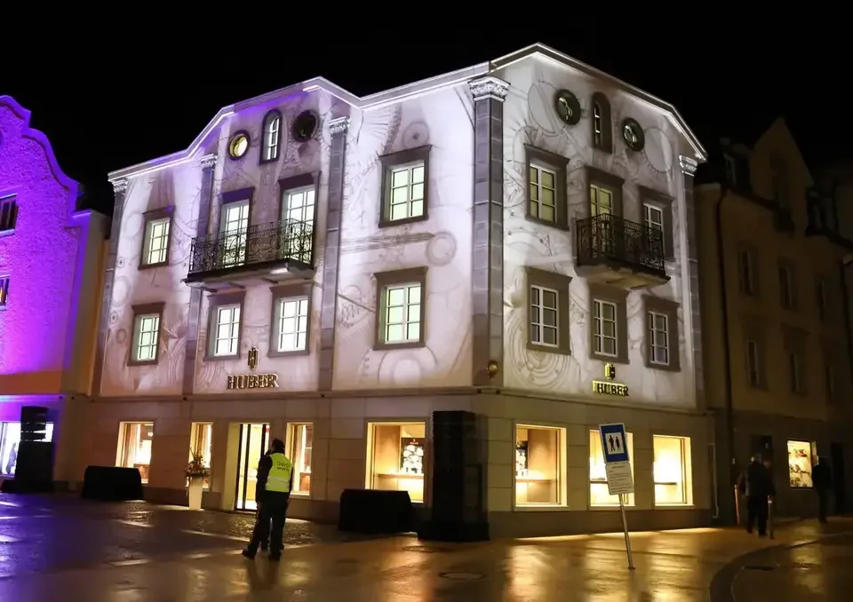Weiße Fassadenprojektion mit architektonischen Konturen – HUBER OPENING, Huber Fine Watches & Jewellery, Bregenz, Österreich