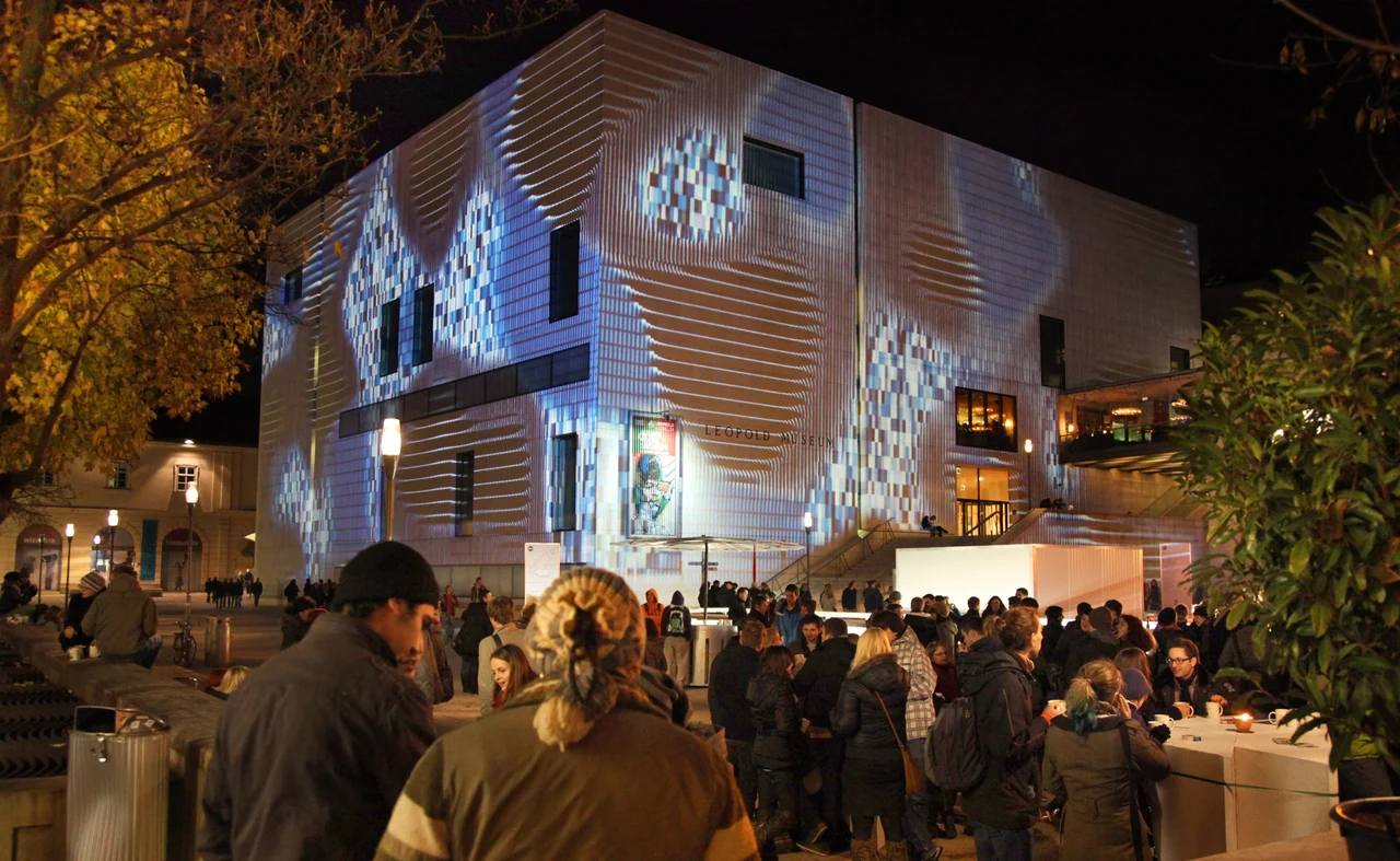 Geometric line and checkerboard projections on the Leopold Museum with an audience in the foreground – WINTER IM MQ, MuseumsQuartier, Vienna, Austria