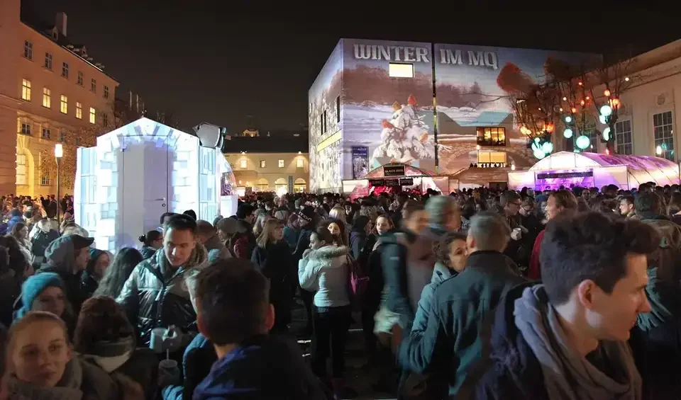 Publikum vor der winterlich projizierten Museumsfassade – WINTER IM MQ, MuseumsQuartier, Wien, Österreich