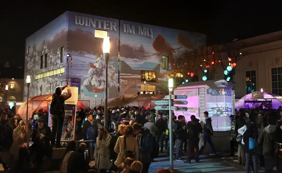 Publikum vor der winterlich projizierten Museumsfassade – WINTER IM MQ, MuseumsQuartier, Wien, Österreich