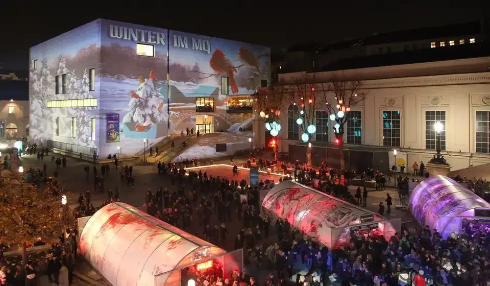 Publikum vor der winterlich projizierten Museumsfassade – WINTER IM MQ, MuseumsQuartier, Wien, Österreich