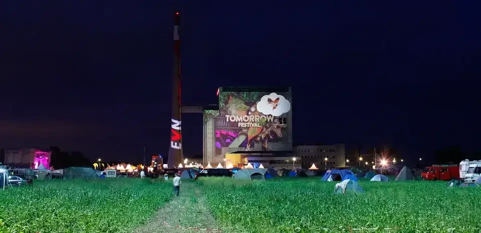 Weite Festivalansicht mit projiziertem Kraftwerksgebäude und Schornstein – TOMORROW FESTIVAL, Kernkraftwerk, Zwentendorf, Österreich