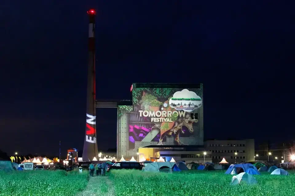 Weite Festivalansicht mit projiziertem Kraftwerksgebäude und Schornstein – TOMORROW FESTIVAL, Kernkraftwerk, Zwentendorf, Österreich