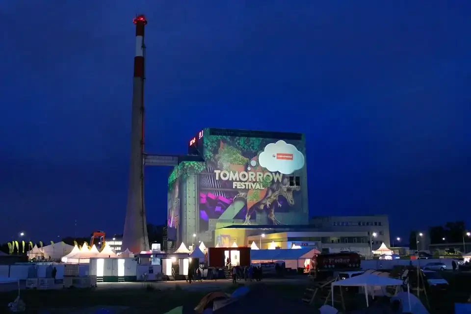Weite Festivalansicht mit projiziertem Kraftwerksgebäude und Schornstein – TOMORROW FESTIVAL, Kernkraftwerk, Zwentendorf, Österreich