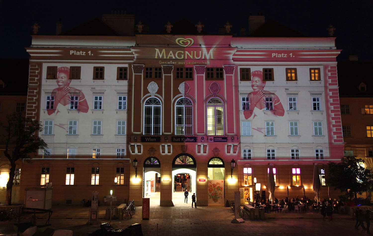 Portrait and brand imagery in pink and black projected onto a facade – MAGNUM PINK BLACK, MuseumsQuartier, Vienna, Austria