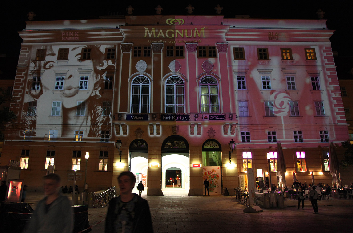 Portrait and brand imagery in pink and black projected onto a facade – MAGNUM PINK BLACK, MuseumsQuartier, Vienna, Austria