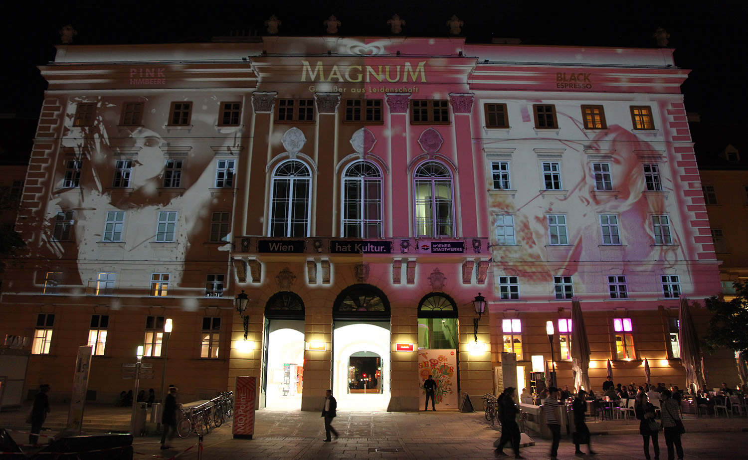 Portrait and brand imagery in pink and black projected onto a facade – MAGNUM PINK BLACK, MuseumsQuartier, Vienna, Austria