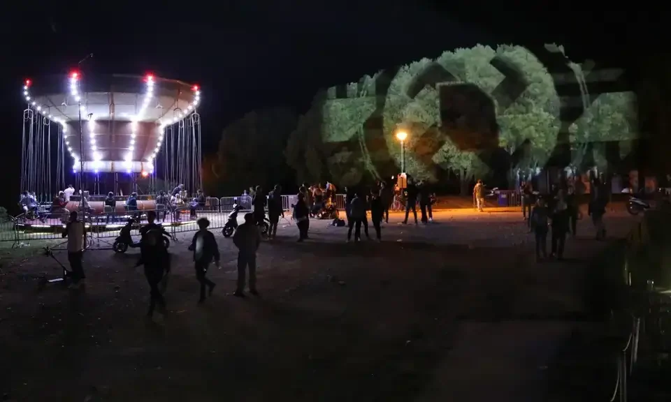 Geometrische Projektionen auf Bäume neben einem Fahrgeschäft – LIGHTHOUSE FESTIVAL 2017, Poreč, Kroatien