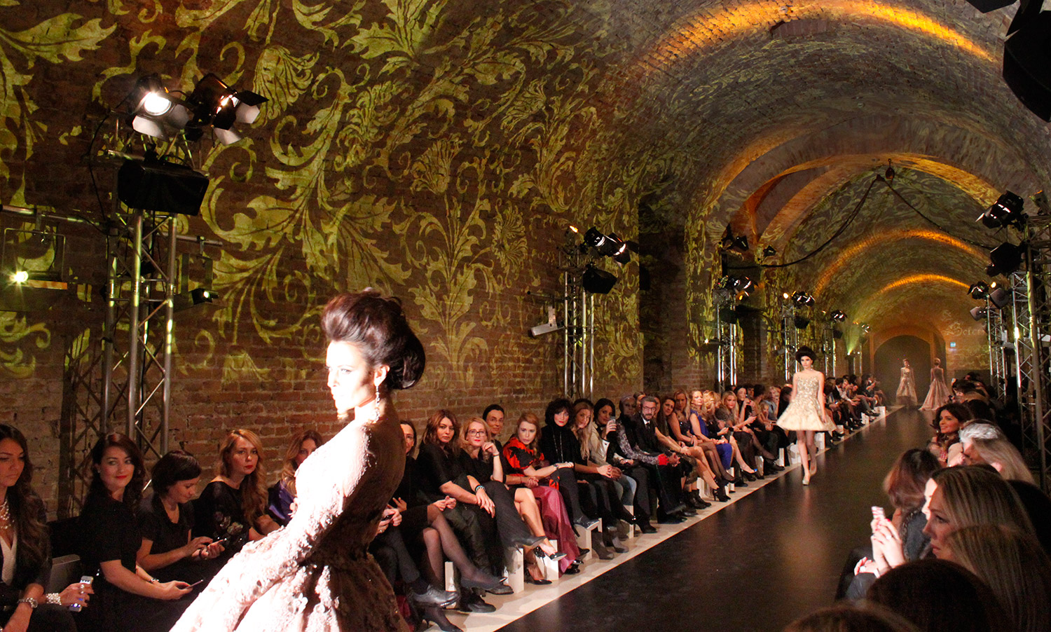 Models on the runway beneath golden vault projections – Solomia Modenschau, Palais Coburg, Vienna, Austria
