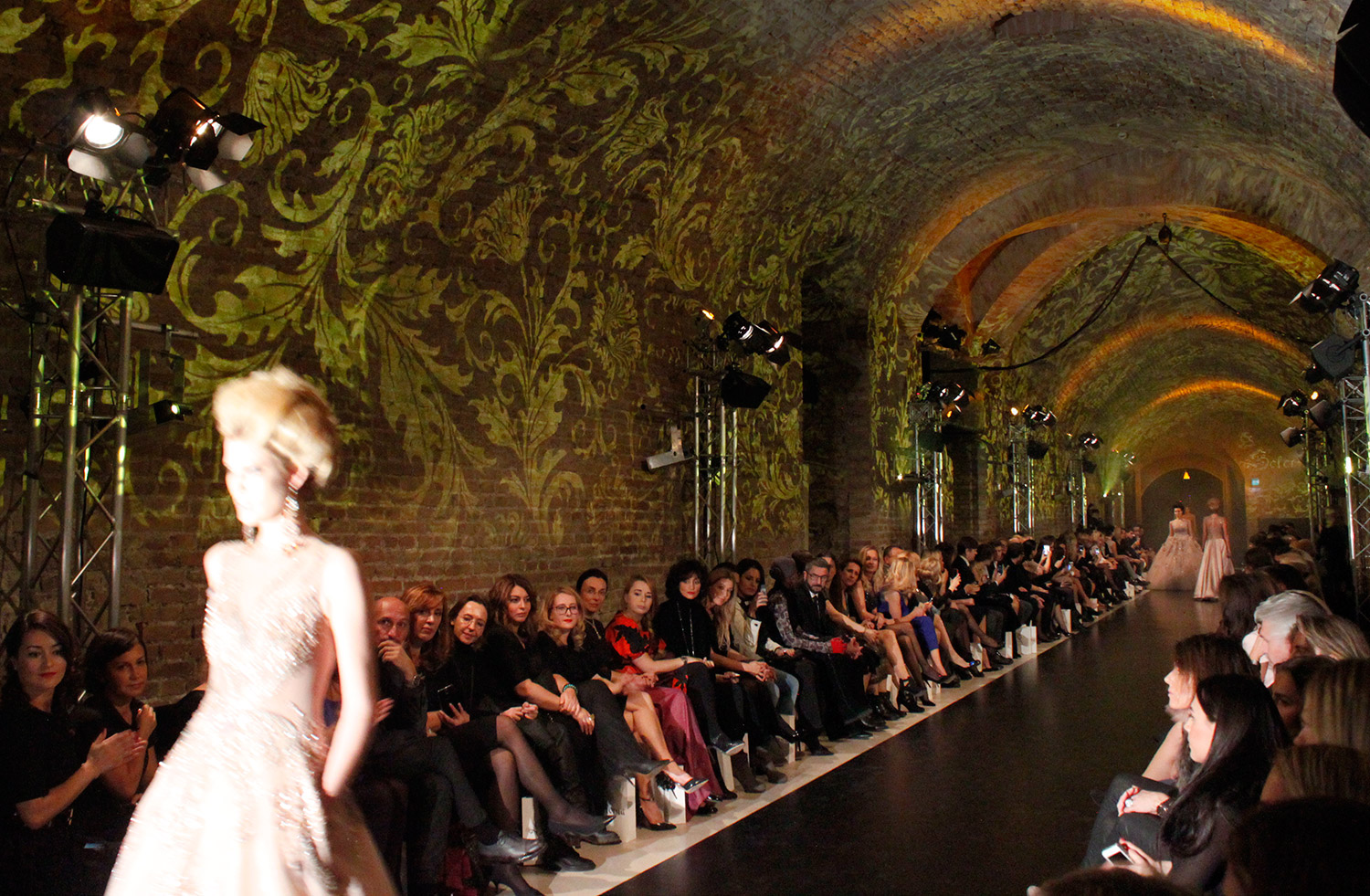 Models on the runway beneath golden vault projections – Solomia Modenschau, Palais Coburg, Vienna, Austria
