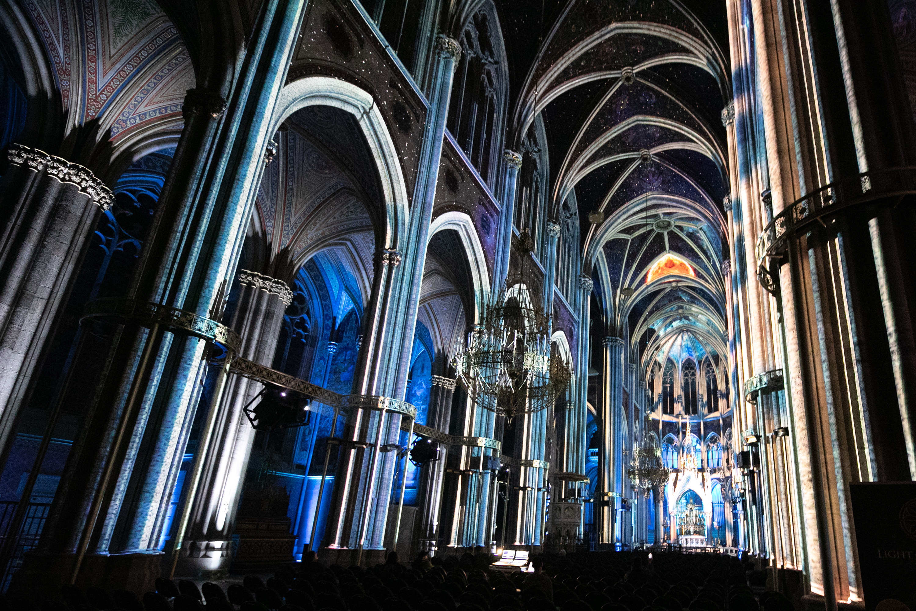 Blaue und goldene Projektionen entlang der Kirchengewölbe – LIGHT OF CREATION, Votivkirche, Wien, Österreich