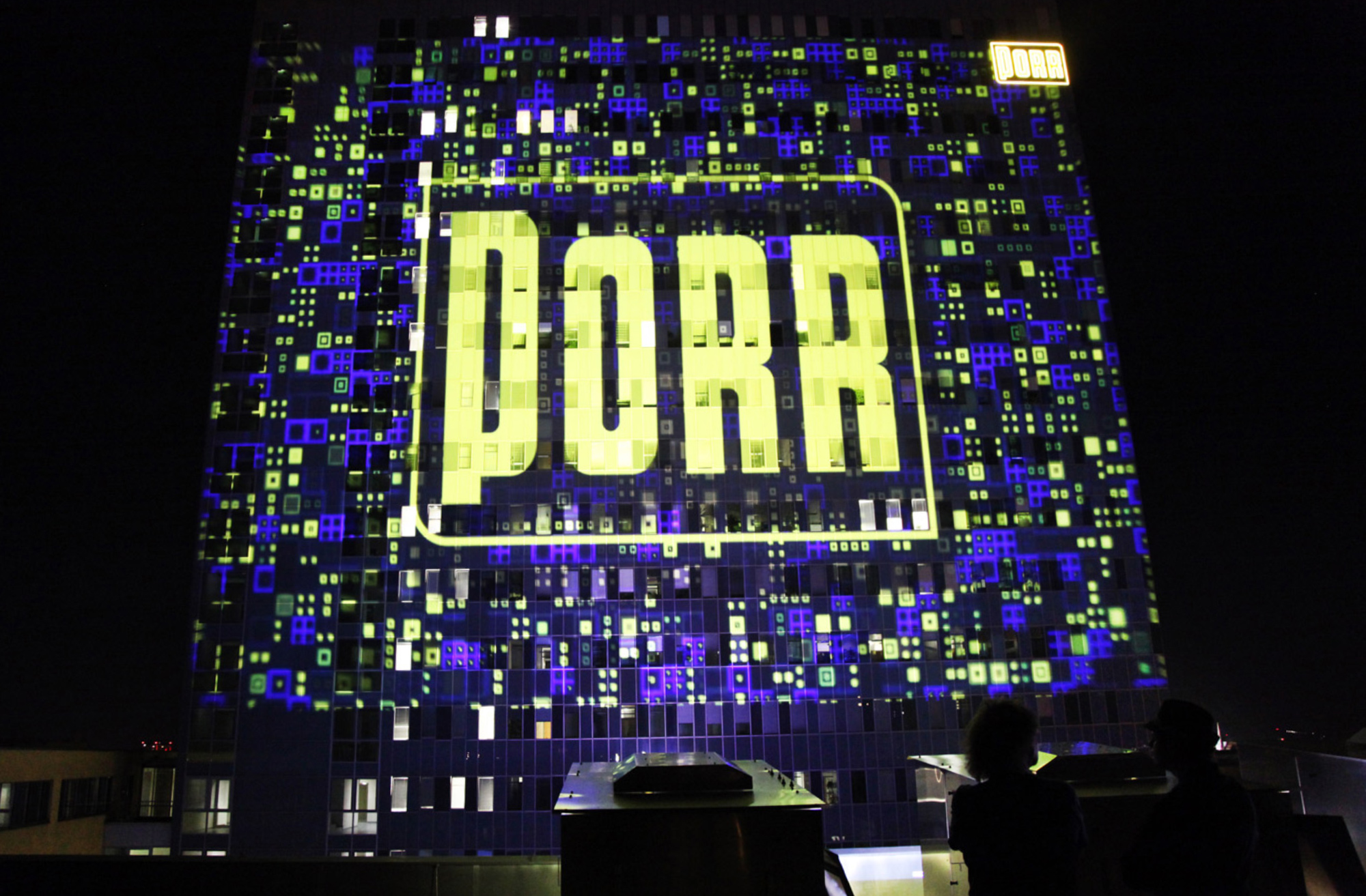 Gelbes PORR-Logo in einer blau-gelben Rasterprojektion auf der Fassade – PORR, Porr Gebäude, Wien, Österreich