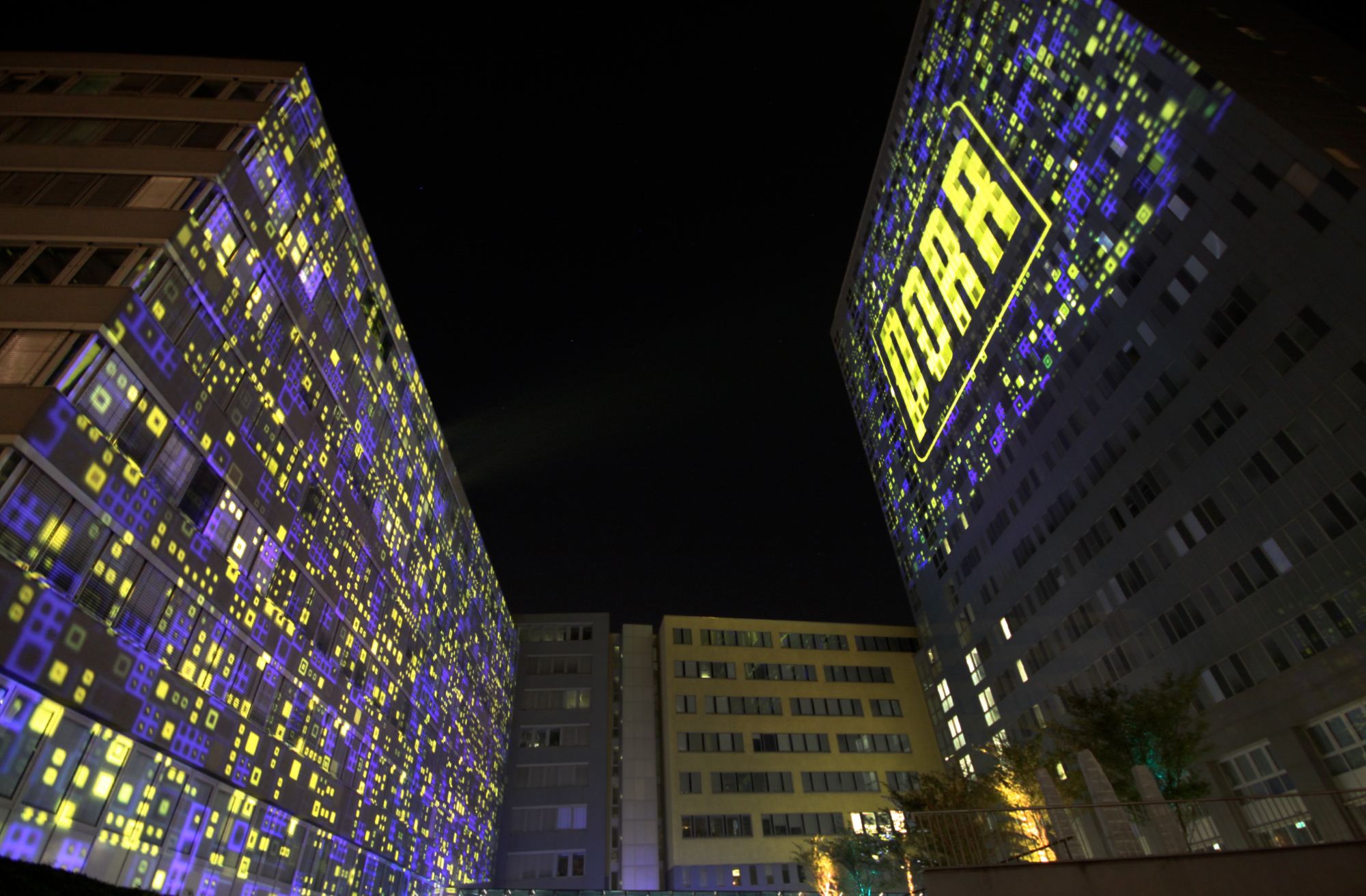 Zwei Gebäudefassaden mit blau-gelben Großbildprojektionen – PORR, Porr Gebäude, Wien, Österreich