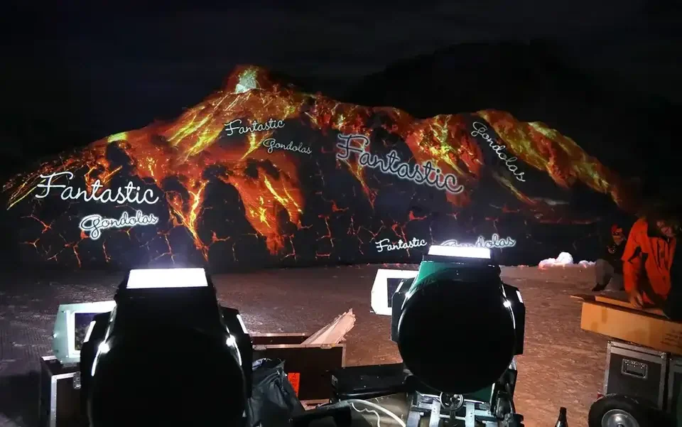 Feuer- und Lavamotive als Großbildprojektion auf einen verschneiten Berg – FANTASTIC GONDOLAS, Lech, Österreich