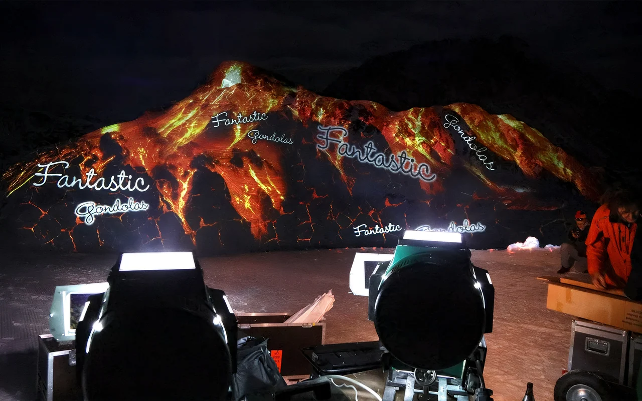 Feuer- und Lavamotive als Großbildprojektion auf einen verschneiten Berg – FANTASTIC GONDOLAS, Lech, Österreich
