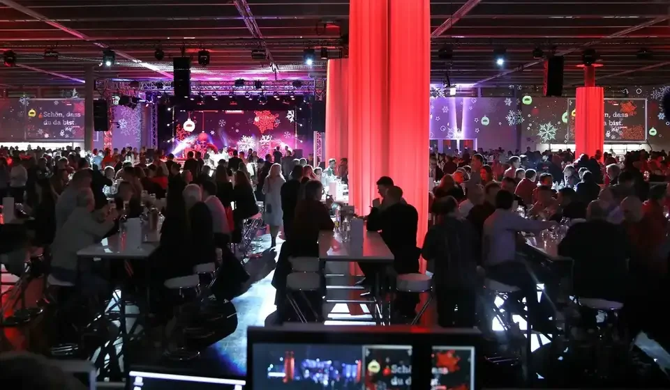 Videosteuerung im Vordergrund des rot beleuchteten Festsaals – A1 Weihnachtsfeier, Austria Center, Wien, Österreich