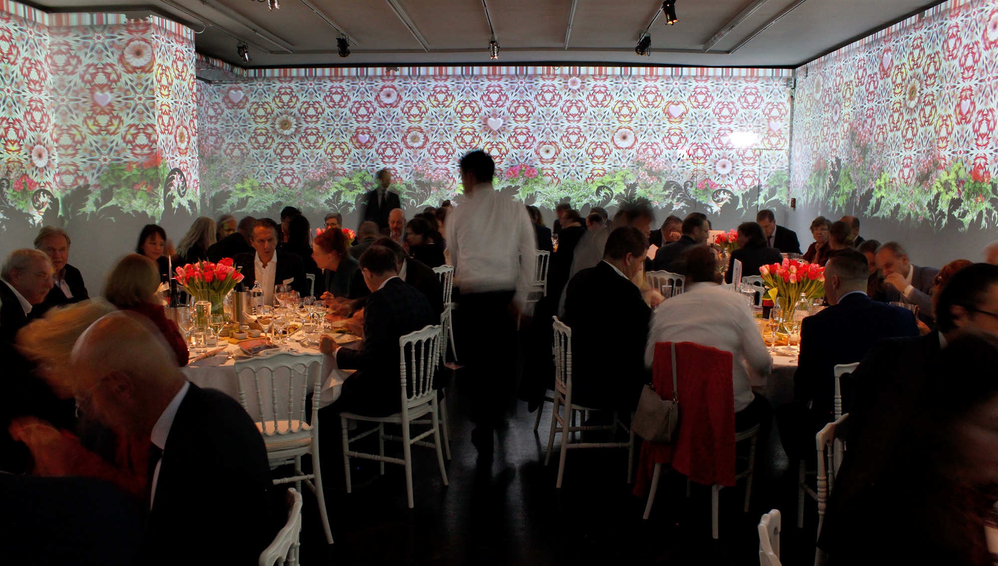 Colourful ornamental and plant imagery projected behind dining tables – Art Brut, Kunstforum, Vienna, Austria