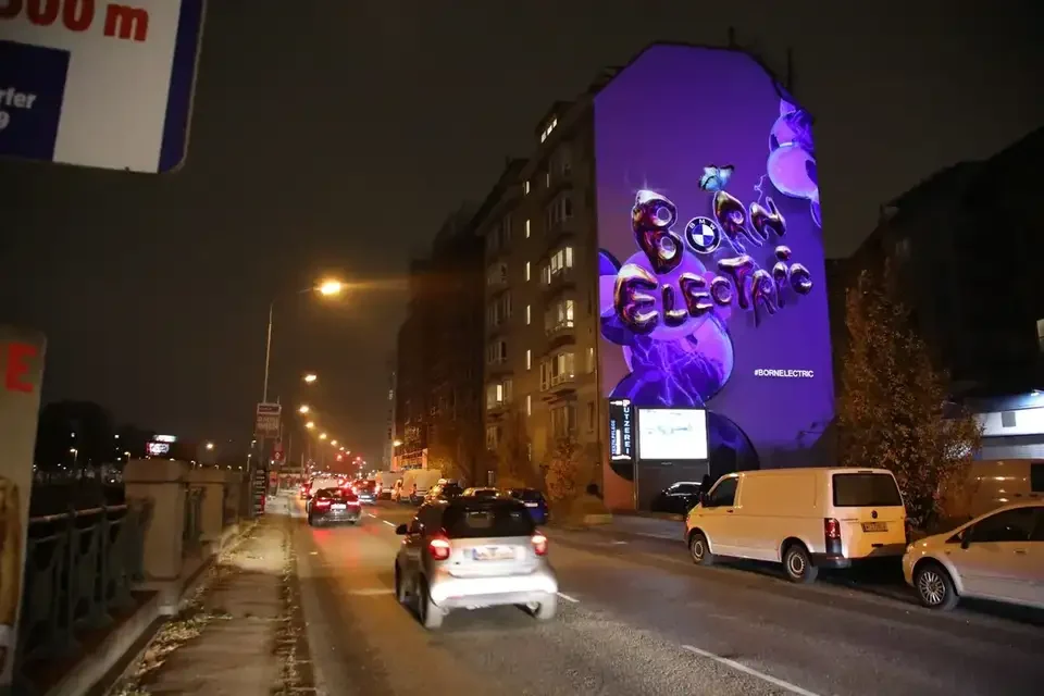 Straßenansicht mit beleuchteter Mural-Projektion und Verkehr – BMW - BORNELECTRIC, Wien, Österreich