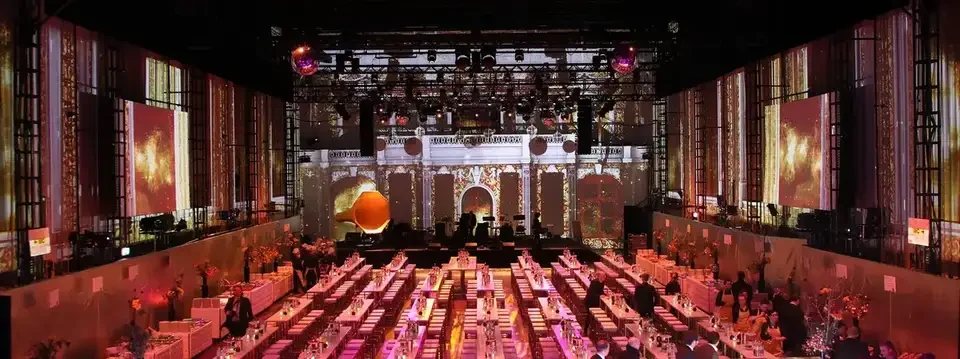 Lange Festtafeln vor rot-weißen Projektionen mit Bogenmotiven – POST HALLE E, Halle E, MuseumsQuartier, Wien, Österreich