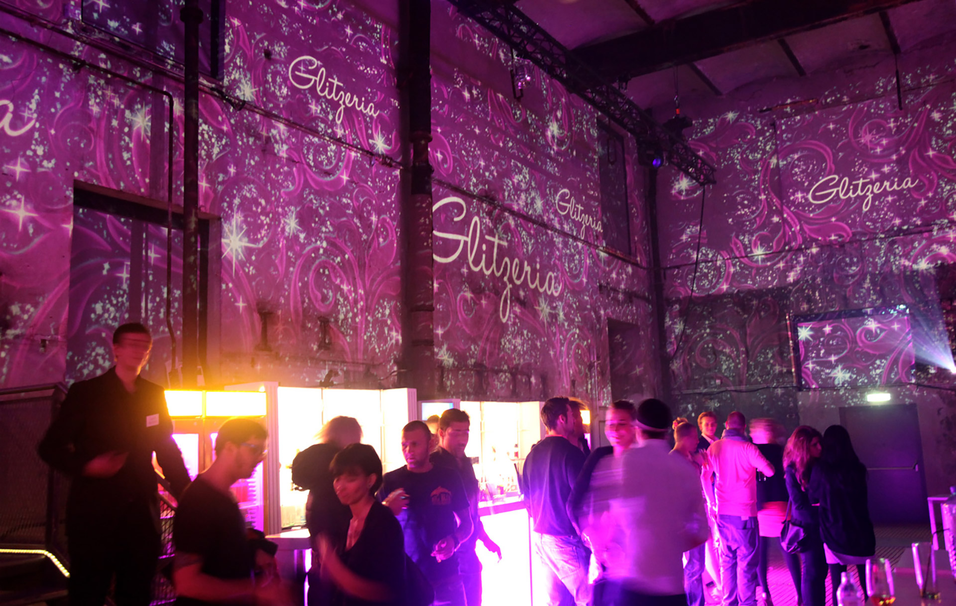 Gäste vor pinken Raumprojektionen und Glitzeria-Schriftzügen – GLITZERIA, Ottakringer Brauerei, Wien, Österreich