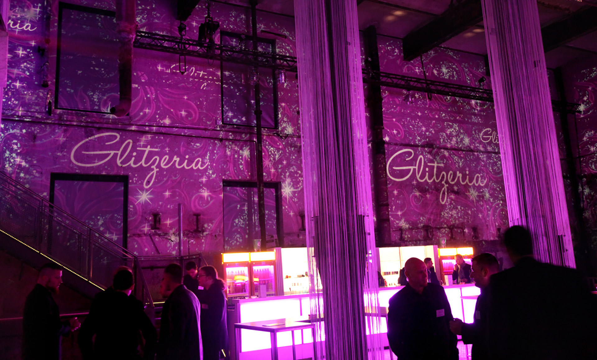 Gäste vor pinken Raumprojektionen und Glitzeria-Schriftzügen – GLITZERIA, Ottakringer Brauerei, Wien, Österreich
