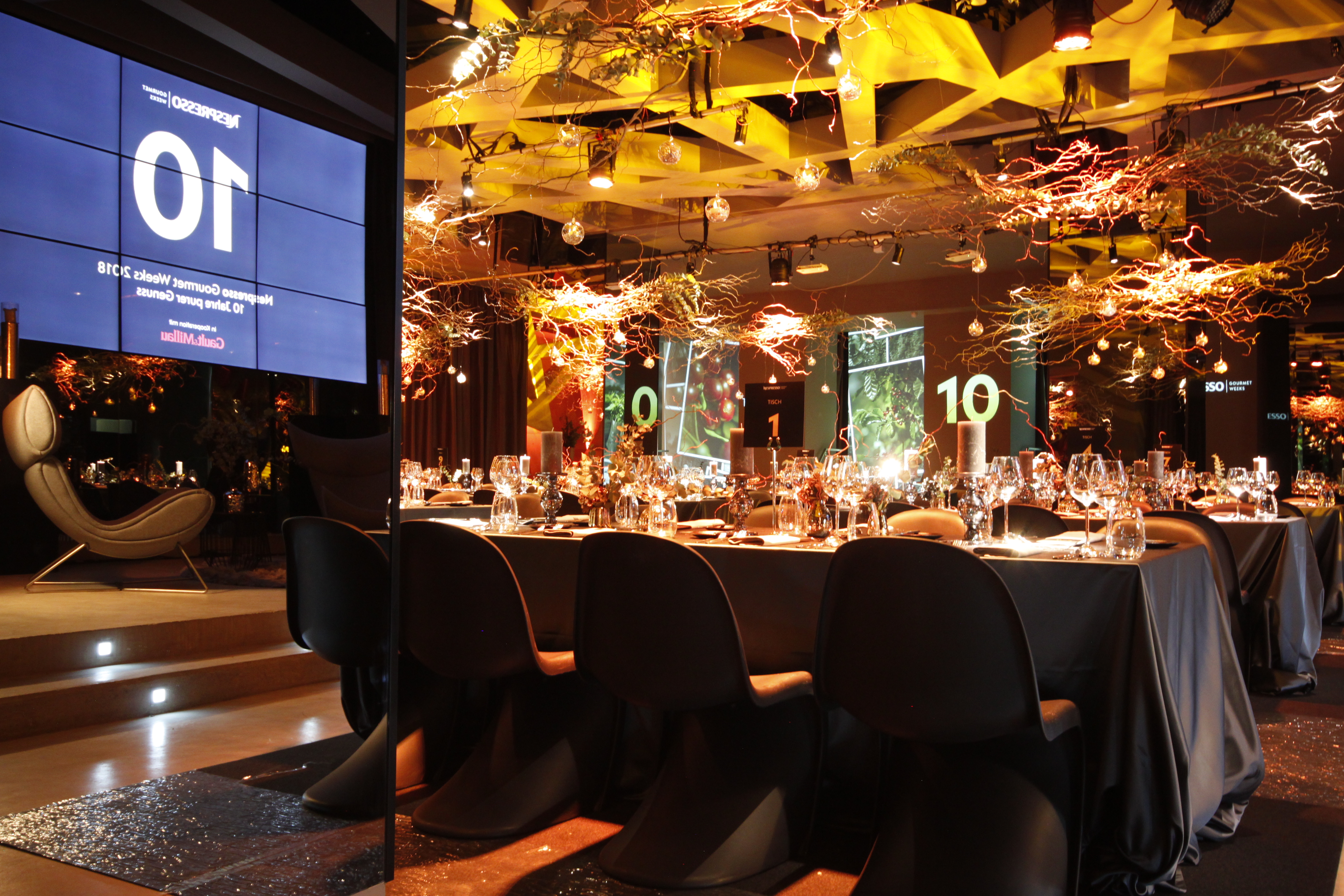 Dining tables beneath light installations in front of spatial projections – Nespresso, Palais Wertheim, Vienna, Austria