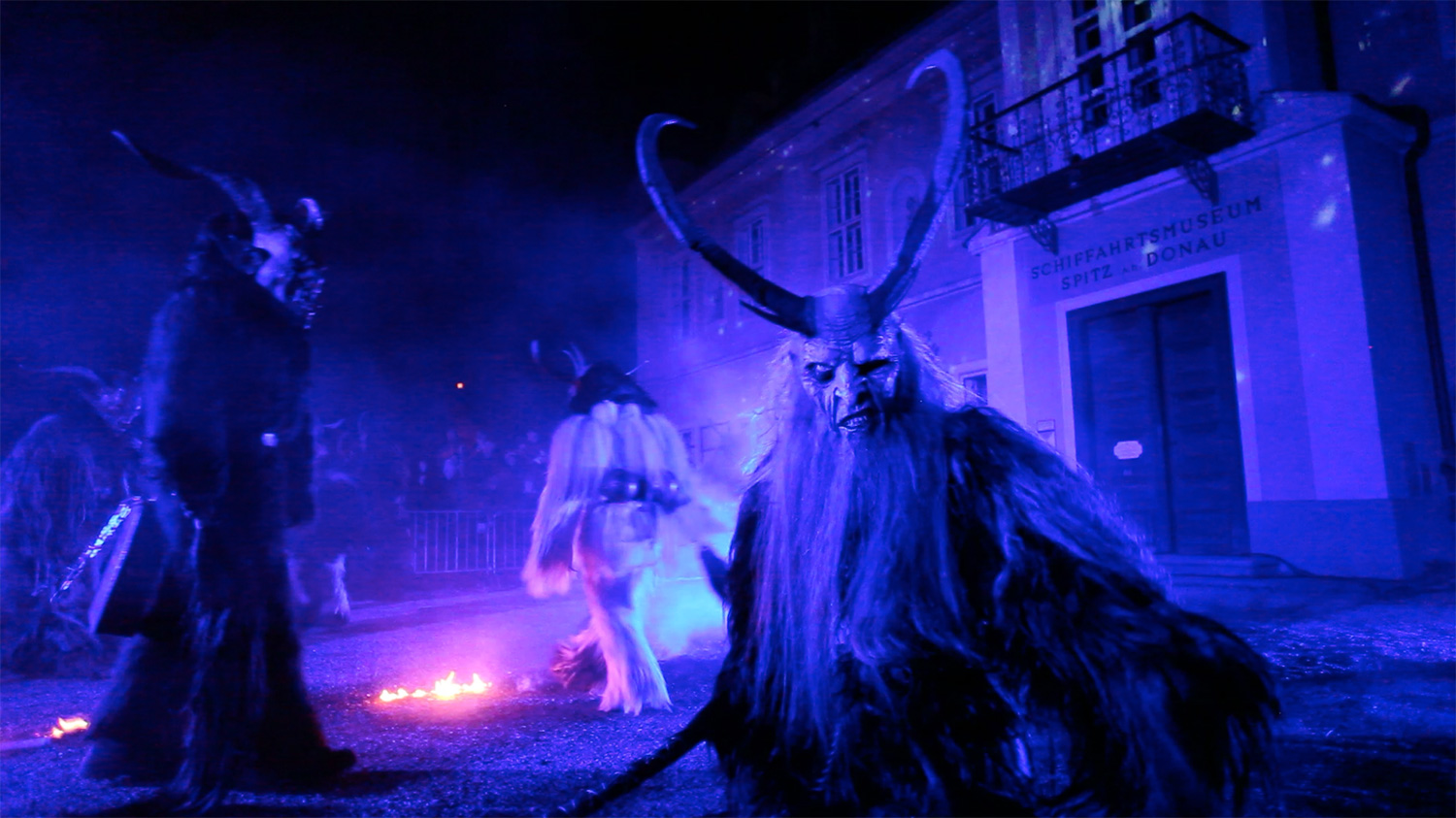 Krampusfiguren unter blauem Licht vor der Rathausfassade – Wachauer Advent, Videomapping in Spitz, Wachau, Österreich