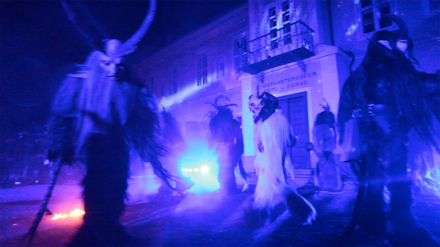 Krampusfiguren unter blauem Licht vor der Rathausfassade – Wachauer Advent, Videomapping in Spitz, Wachau, Österreich